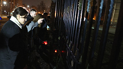 Представители общественности и молодежь несут цветы и лампады к посольству России в Минске
